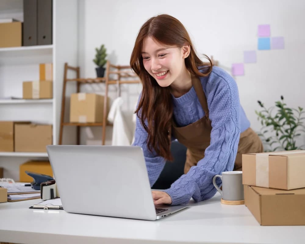 Small business owner managing online orders on a laptop through an e commerce web portal.